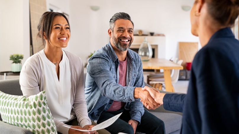 Couple shaking real estate specialist's hand